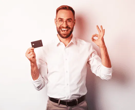 Photograph of a man with a white shirt holding a credit card on one hand and makin an "ok" sign on the other