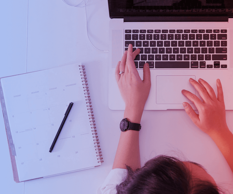 Photograph of a women using a laptop and a notebook with a pencil